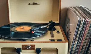 Klasyczny gramofon z płytą winylową i stosem okładek płyt. To jest właśnie to, co to jest gramofon – urządzenie do odtwarzania muzyki z płyt.