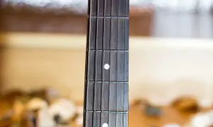 Zbliżenie na gryf gitary z widocznymi progami i strunami. Palce gitarzysty zaraz zaczną tworzyć melodię.