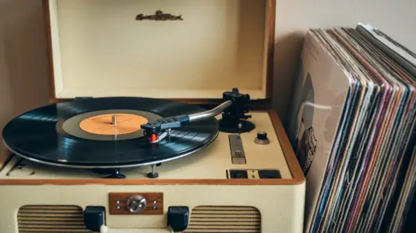 Klasyczny gramofon z płytą winylową i stosem okładek płyt. To jest właśnie to, co to jest gramofon – urządzenie do odtwarzania muzyki z płyt.